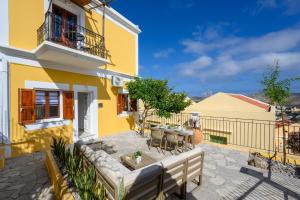a yellow house with a table and chairs on a patio at Elpidas Apartments in Symi