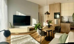 a living room with a large television and a table at Apartmán PLÁŇ Vesna Resort in Vysoké Tatry