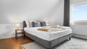 a bedroom with a large white bed with a window at Moderne Wohnung - Nähe Messe / Flughafen in Lohmar +20 photos