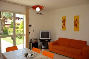 ein Wohnzimmer mit einem orangenen Sofa und einem TV in der Unterkunft Villa Achillea - villetta con jacuzzi privata e piscina condominiale in Mascali