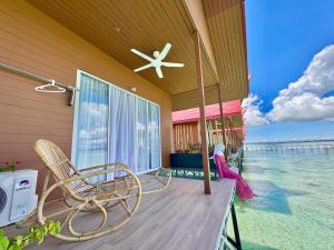 un porche avec une chaise et un ventilateur et l'océan dans l'établissement Sand Bay Resort Semporna, à Pulau Sabangkat