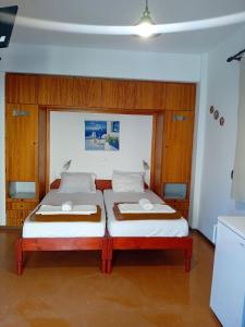 two beds in a room with wood paneling at Kostas Studios Apartments - Ενοικιαζόμενα δωμάτια με κουζινάκι in Mirina
