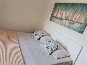 a bed with two pillows and a painting on the wall at Apartment Sun & Sea in Krk