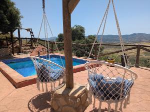 two chairs on a swing next to a swimming pool at Casa KiSi Cottage, Rural Boutique Bed & Breakfast in Málaga