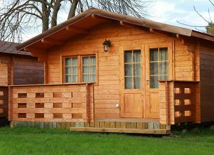 a wooden cabin with a door in the grass at Nemirsetos Nameliai in Palanga