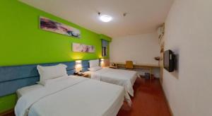 7 Days Inn Wuhan Hanzheng Street Shengli Road Metro Station في ووهان: غرفة بسريرين وجدار أخضر