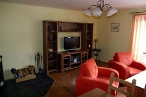 a living room with two red chairs and a television at Pension Strnad in Velká Úpa