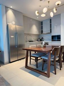 a kitchen with a wooden table and a refrigerator at Address Beach Resort Fujairah Apartment by Blue World - 3 in Fujairah
