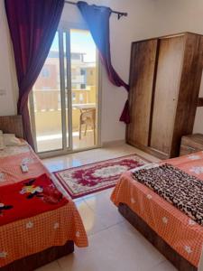 a bedroom with two beds and a sliding glass door at شاليه بالساحل الشمالى قرية نيو كوست الكيلو 77 قبلى الطريق بشاطىء خاص in El Alamein