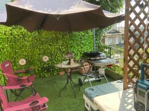 a patio with an umbrella and chairs and a grill at Cool Treasure 7 in Kami-tatsuda