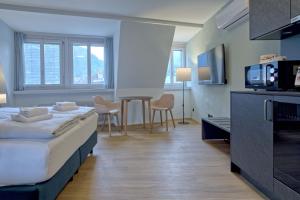 una habitación de hotel con 2 camas y una mesa con sillas en BANK House Studio M 405 - GRIWA RENT, en Interlaken