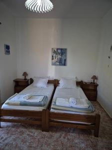 two twin beds in a bedroom with a chandelier at Kostas Studios Apartments - Ενοικιαζόμενα δωμάτια με κουζινάκι in Myrina