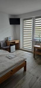 a bedroom with a bed and a desk and windows at UniBal - pokoje gościnne in Unieście