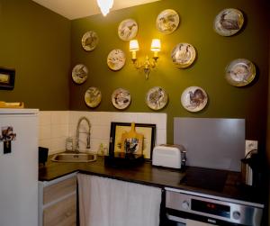a kitchen with plates on the wall and a sink at Centre historique de LYONS LA FORET Hotel de Maître le Cottage in Lyons-la-Forêt