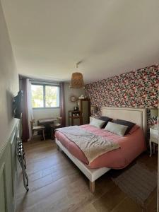 a bedroom with a large bed and a wall covered in wallpaper at Au gré des vents in Saint-Quay-Portrieux