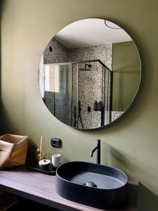 a bathroom with a large round mirror above a sink at VILLAREJA - Stilvolle ruhige Boutique-Suite mit Terrasse, Designbad und Altstadtblick im Herzen von Bozen in Bolzano +27 photos