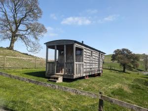 a tiny house sitting in a field next to a fence at The Wagon, rustic off grid experience in Ashbourne