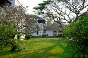 a yard with a white house and trees at Brunton Boatyard - CGH Earth in Cochin