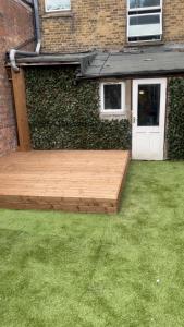 Forest HillにあるCozy Two Bedroom Flat 1 Minute from Forest Hill Train Stationの建物の隣の庭の木製デッキ