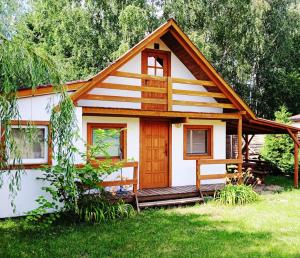 a small cabin with a porch in a yard at Ogrzewany domek nad jeziorem, mazury in Szczytno