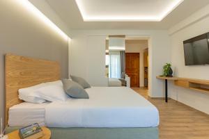 a bedroom with a white bed and a television at Archontiko Liamas in Stavros