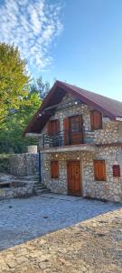 a stone building with wooden doors and windows at VD Forest villa in Cetinje