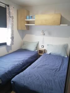 Dos camas una al lado de la otra en una habitación. en Mobil home Menanteau, en Les Mathes