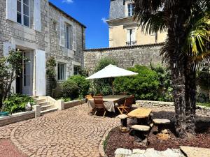 patio z parasolem, stołem i krzesłami w obiekcie Maison de charme de 280m2 avec piscine chauffée … w mieście Luçon