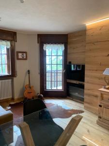sala de estar con mesa y guitarra en Bijoux sulle piste, en Sauze d'Oulx