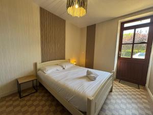 a bedroom with a white bed with a window and a chandelier at L'endurance 24 in Teloché
