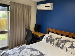 a bedroom with a bed and a desk with a computer at Self Contained Room in Hillsborough in Auckland