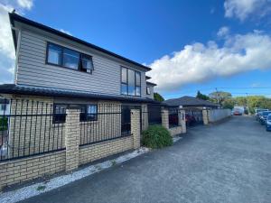a house with a fence next to a parking lot at Self Contained Room in Hillsborough in Auckland