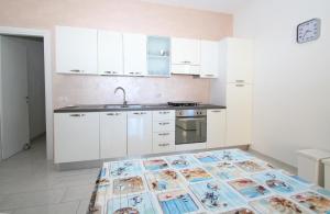 a kitchen with white cabinets and a table with a pattern on it at Palau Fonte Vecchia Apartment in Palau
