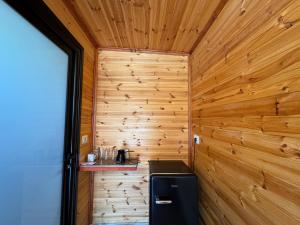un piccolo bagno con pareti in legno e un frigorifero di The Pool Pushi Park a Ksamil
