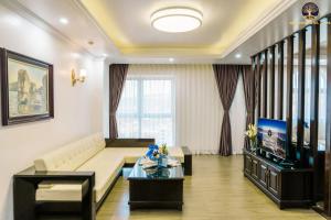 Una sala de estar con un sofá y un televisor. en New Era Hotel & Spa Ha Long, en Ha Long