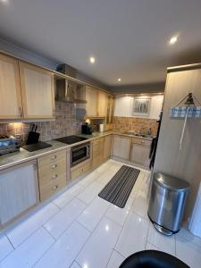 a large kitchen with wooden cabinets and a refrigerator at TorquayTownhouse with Hot Tub 200m from Beach - Free WiFi Sky Glass in Torquay
