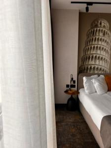 a bedroom with a bed and a curtain with the leaning tower at MM Boutique Hotel in Burgas