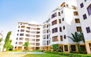 a large white apartment building with a park in front of it at Impala Suites in Mombasa