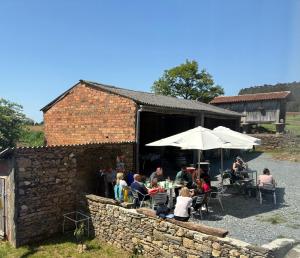 a group of people sitting at a table with an umbrella at A casa do Rio - The River House in Arzúa