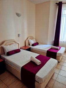 a hotel room with two beds and a window at Impala Suites in Mombasa +8 photos