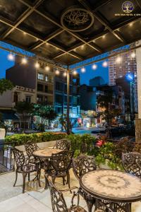 Un patio al aire libre con mesas y sillas por la noche. en New Era Hotel & Spa Ha Long, en Ha Long