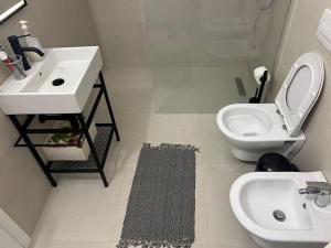 a white bathroom with a sink and a toilet at Katoria Bridge Apartment in Vlorë