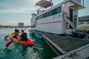 zwei Personen in einem Kajak neben einem Boot in der Unterkunft Exclusivas vistas al mar en casa barco, pleno centro, terraza, parking in A Coruña