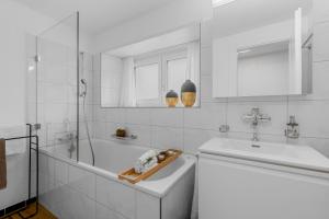 a white bathroom with a tub and a sink at Ferienwohnung 'Rosmarin' Schiers in Schiers +16 photos