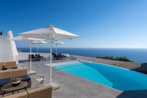 a swimming pool with chairs and umbrellas and the ocean at La Maltese Residence in Imerovigli
