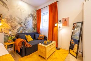 a living room with a blue couch and orange curtains at Smart Studio, AC ,Fast Wi-Fi & Walk to Marina by QuickTrips in Taʼ Xbiex