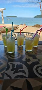 a group of four glasses with straws on a table near the beach at Pousada Cabanas Paraiso in Ilha Grande