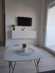 een witte woonkamer met een tafel en een tv bij Monami - Apartman Simona in Vodice