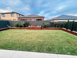 a backyard with a fence and a grass yard at Mt Atkinson Retreat in Truganina