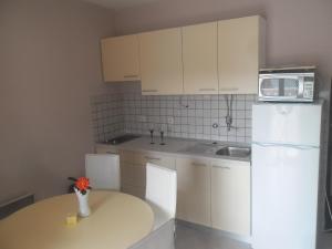a kitchen with white cabinets and a table with a microwave at Apartments Dunja Piric in Lopar